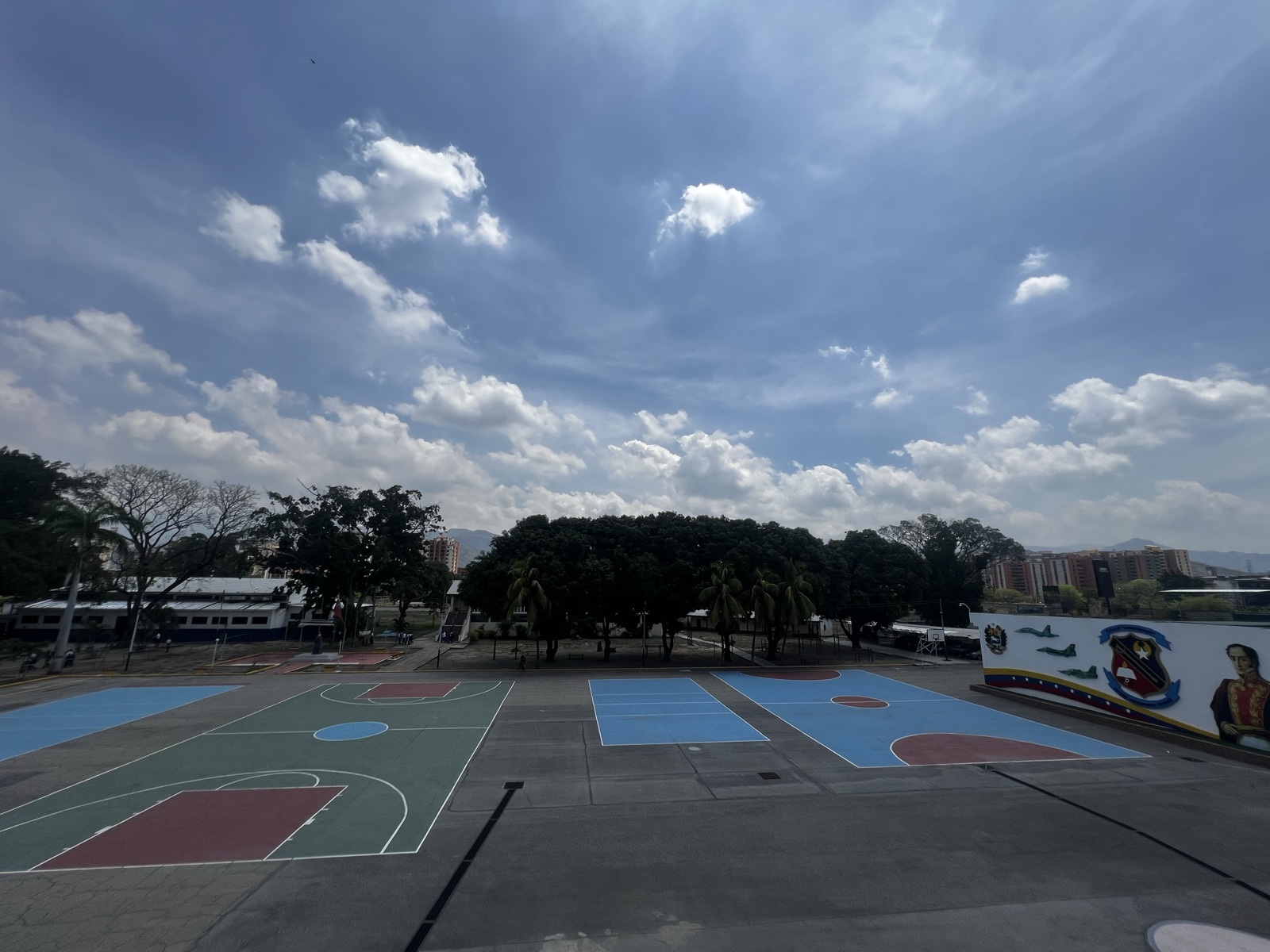 Vista aérea del patio principal del Liceo Militar Libertador con las canchas pintadas y el mural institucional al fondo
